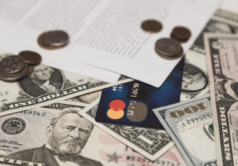 Bank credit card, moneys and coins and bank contract on background.