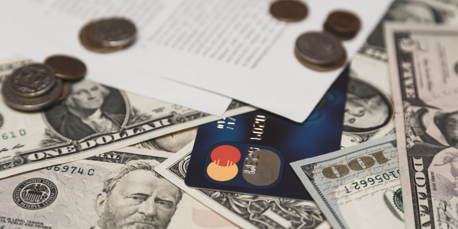 Bank credit card, moneys and coins and bank contract on background.