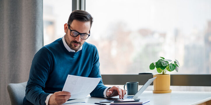 Busy elegant bearded adult company director, checking the company finances, at the office.